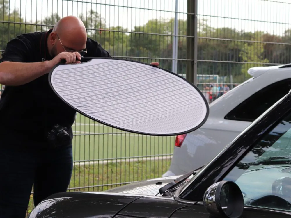 Onur Karagöz prüft mit einem Reflektor die Oberfläche eines Fahrzeugs