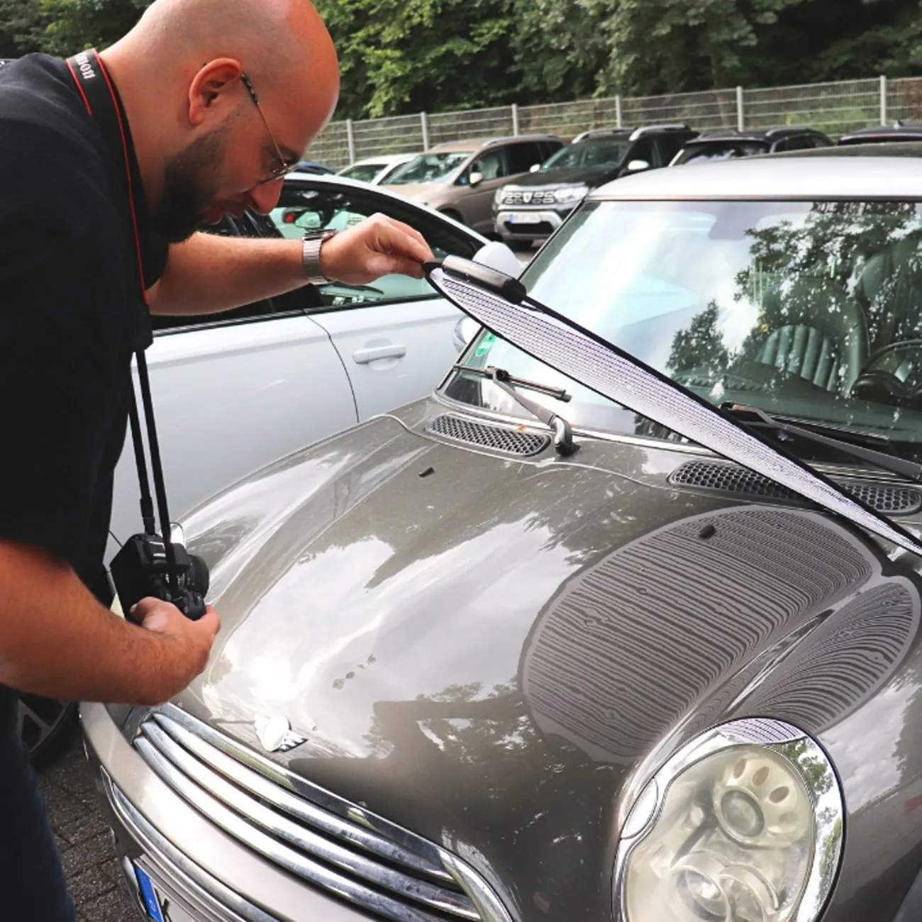 Onur Karagöz prüft den Motorraum eines Fahrzeugs mit geöffneter Haube