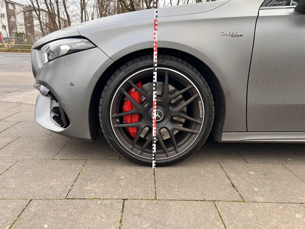 Vermessung an der Seite eines grauen Mercedes-AMG mit Messlatte